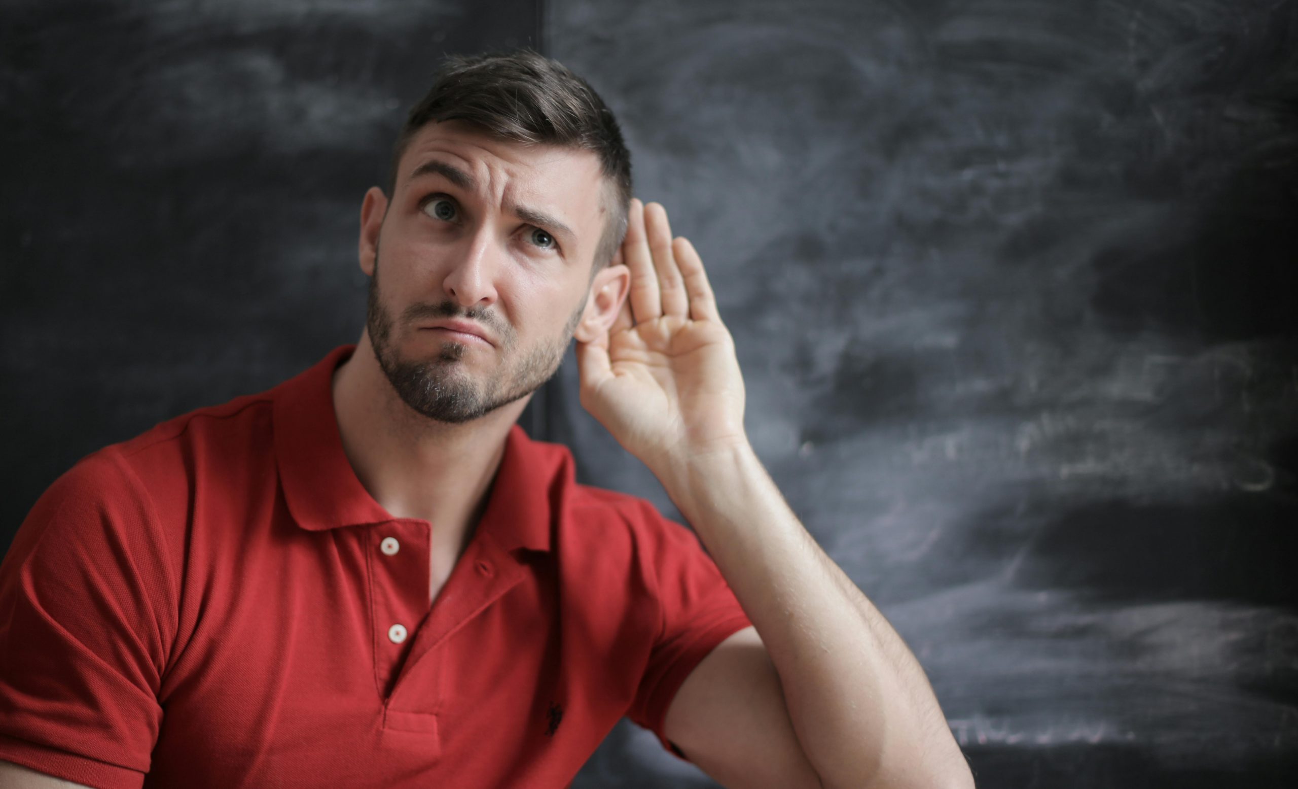 man in a red shirt cupping his ear